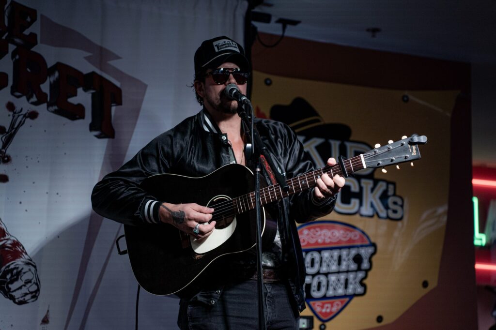 Musician in sunglasses playing an acoustic guitar on stage