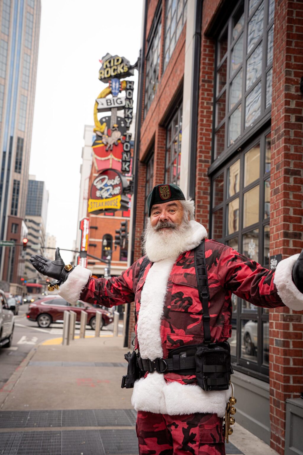 Santa wearing a green beret greeting guests on Broadway in downtown Nashville