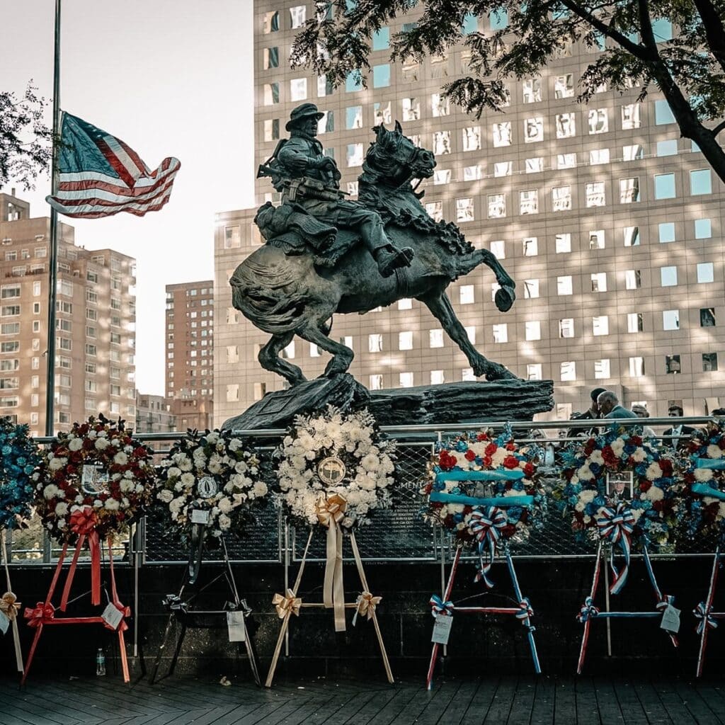 Memorial wreaths placed before America’s Response Monument in Liberty Park, with the American flag at half-staff